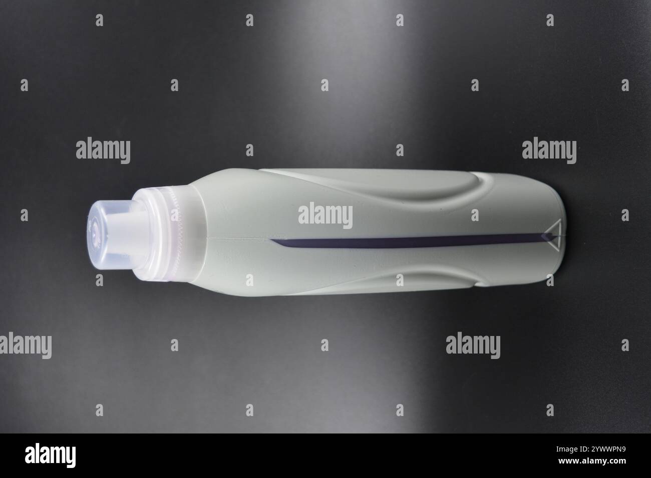 Une grande bouteille grise pour laver les vêtements, linge de lit, tissus. Une bouteille en plastique remplie d'un liquide visqueux violet avec un bouchon transparent. Banque D'Images