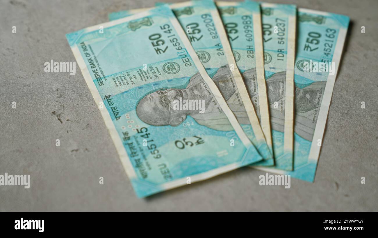 Des billets de banque indiens de cinquante roupies sont étalés sur une surface en béton, mettant en valeur le dessin détaillé et le portrait du mahatma gandhi à la lumière du jour. Banque D'Images