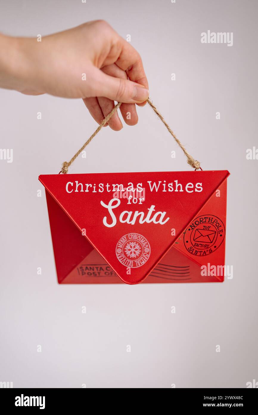 Enveloppe rouge festive remplie de voeux de Noël pour le Père Noël tenu à la main pendant la saison des fêtes Banque D'Images