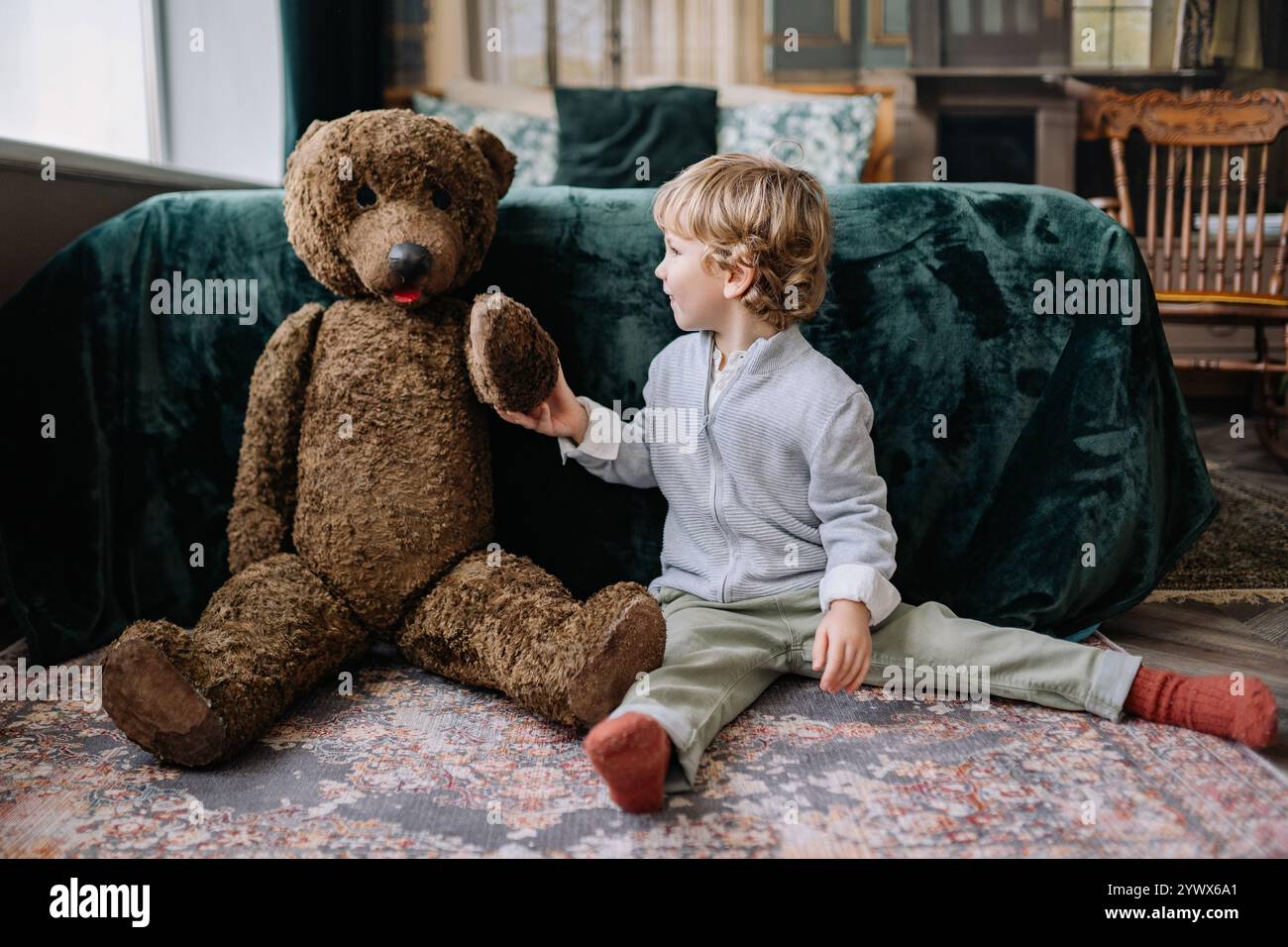 Enfant mignon partageant un moment joyeux avec un grand ours en peluche pendant les fêtes de Noël et du nouvel an à la maison Banque D'Images