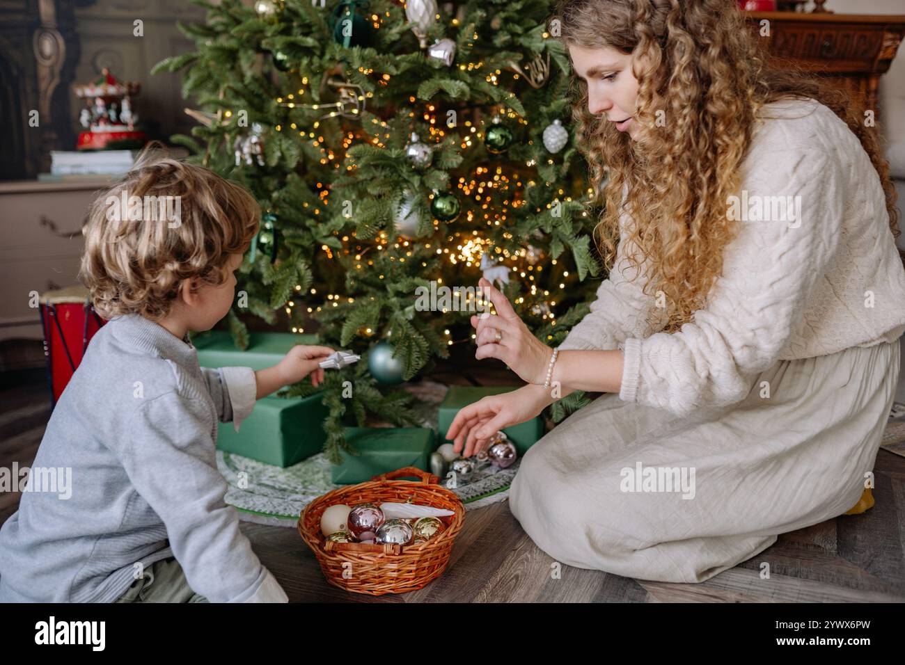 Célébrer Noël et nouvel an avec la famille comme mère et fils décorer l'arbre ensemble dans le salon confortable Banque D'Images