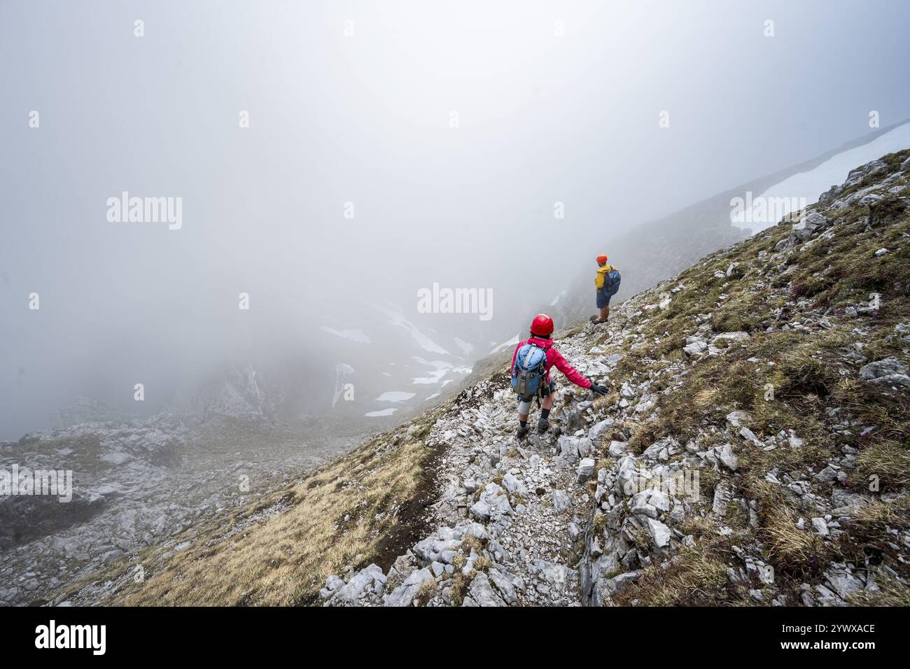 Deux alpinistes sur un étroit sentier de randonnée, ascension à l'Ackerlspitze, nuages se déplaçant autour des montagnes, Wilder Kaiser, montagnes Kaiser, Tyrol, Aus Banque D'Images