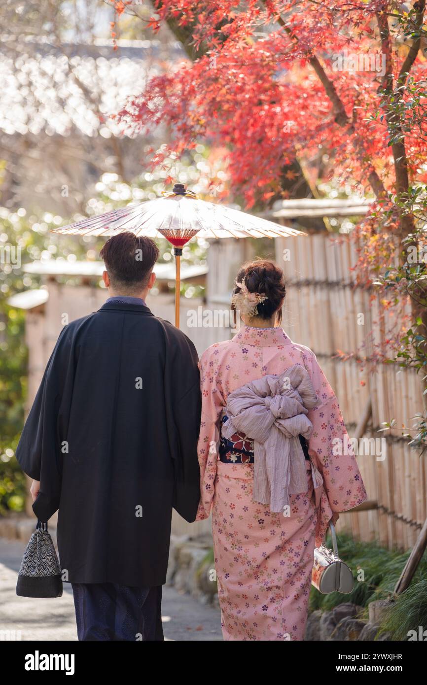 Un couple portant un Kimono avec un parapluie japonais à Kyoto, au Japon. Les feuilles d'érable virent au rouge en automne. Fond traditionnel japonais. Banque D'Images