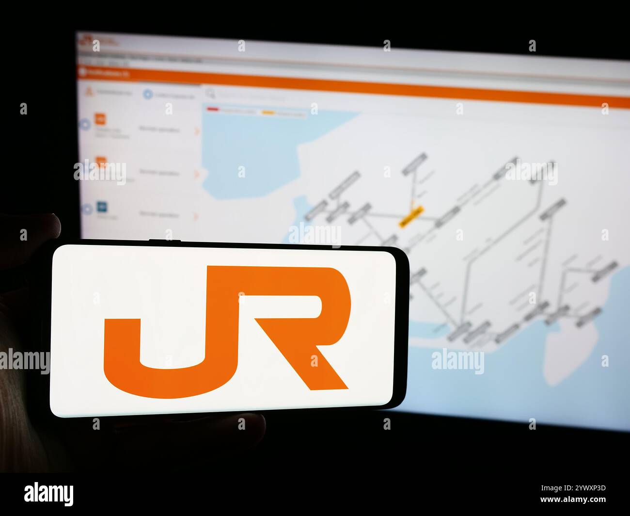 Dans cette illustration photo, une personne tient un téléphone portable avec le logo de l'entreprise ferroviaire japonaise Central Japan Railway Company en face de la page Web. Banque D'Images