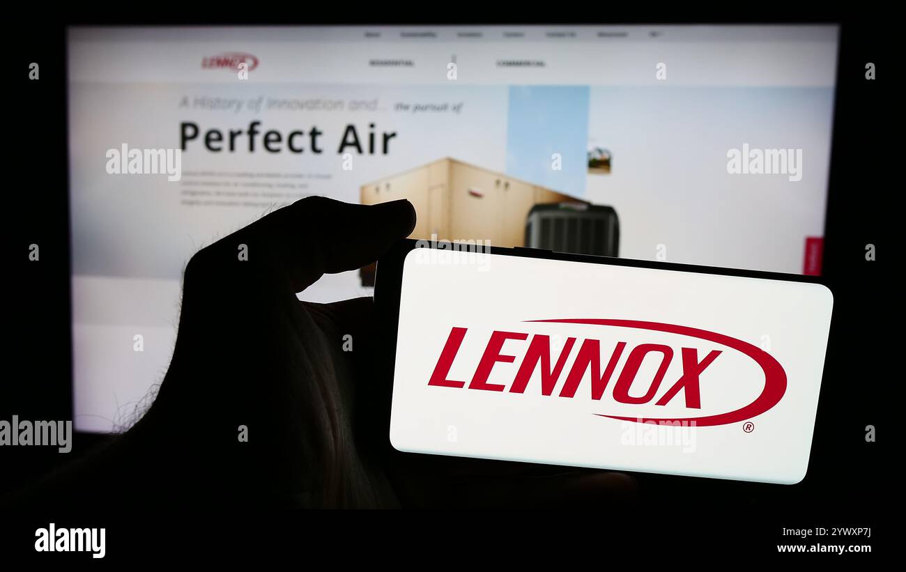 Dans cette illustration photo, une personne tient un smartphone avec le logo de la société américaine Lennox International Inc d'équipement HVAC en face du site Web. Banque D'Images