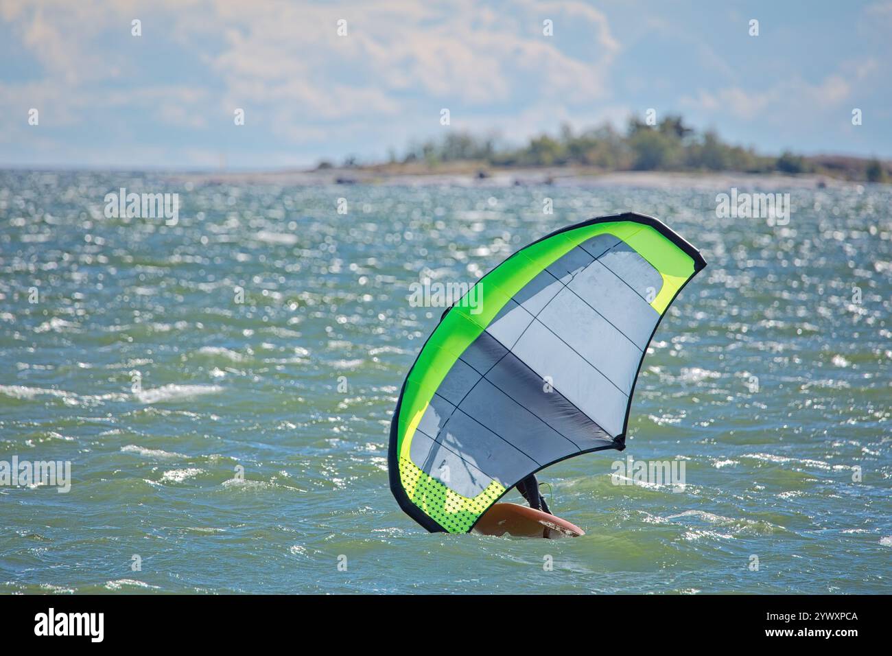 L'homme joue l'aile en utilisant l'aile gonflable portative et la planche de surf hydrofoil en mer en été. Cavalier sur une planche d'aile de vent, surfe les vagues. Banque D'Images