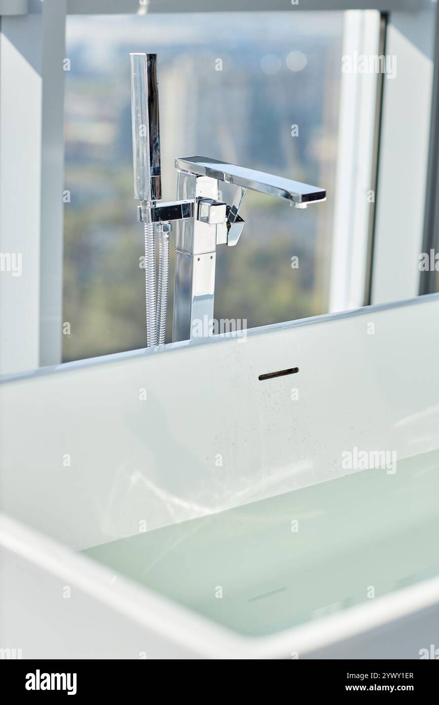 Gros plan sur le robinet de salle de bains chromé sur la baignoire moderne remplie d'eau chaude dans la salle de bains, espace de copie Banque D'Images