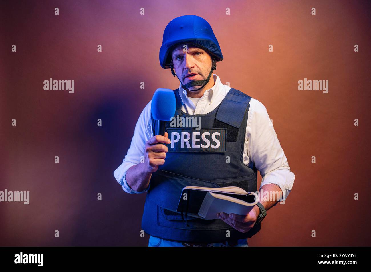 Journaliste avec gilet pare-balles tenant un microphone en studio. Banque D'Images