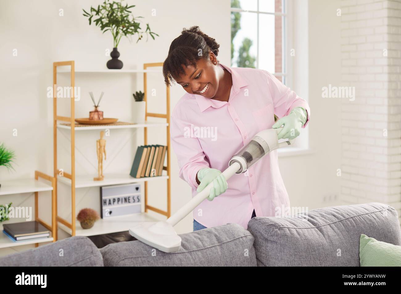 Servante afro-américaine dans un canapé aspirateur uniforme, gros plan Banque D'Images