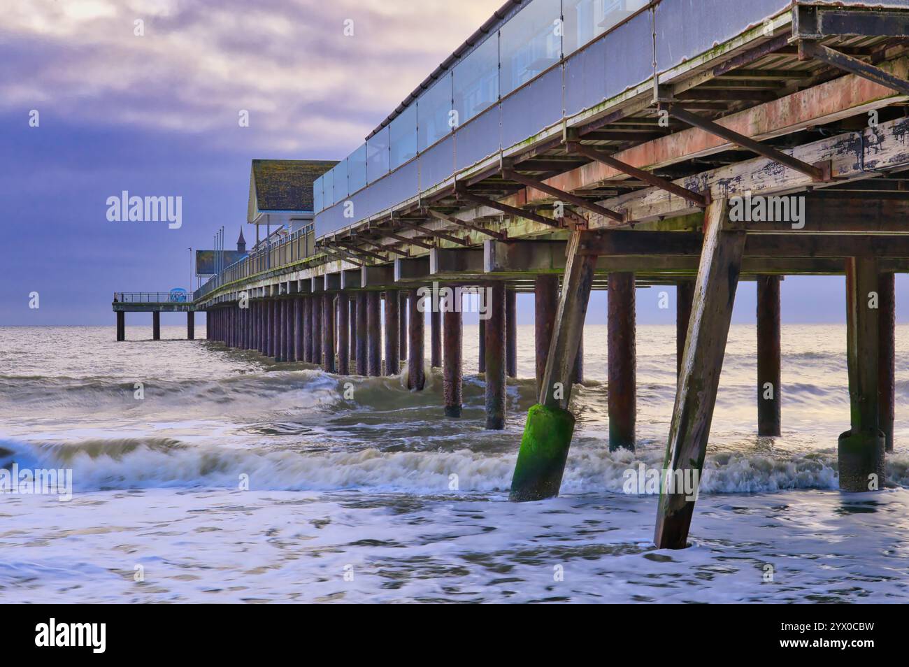 Southwold, Suffolk, Angleterre, Royaume-Uni - regardant sous la jetée Southwold au lever du soleil avec des vagues se brisant autour des supports de jetée en bois Banque D'Images