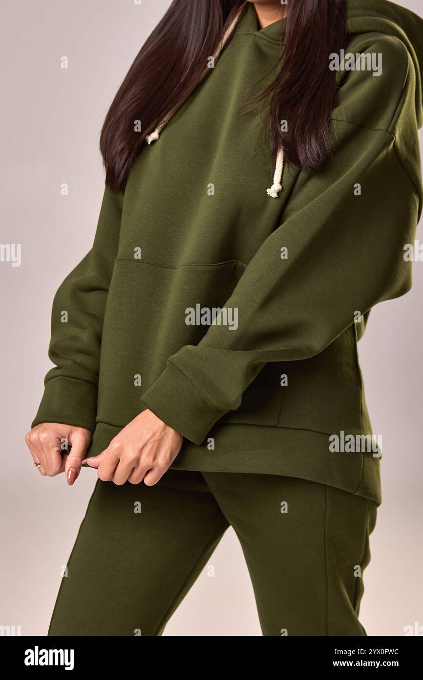 En gros plan montre une femme portant un sweat à capuche vert olive avec des détails de cordon, reflétant un style de mode décontracté confortable, concept de vêtements d'extérieur chauds Banque D'Images