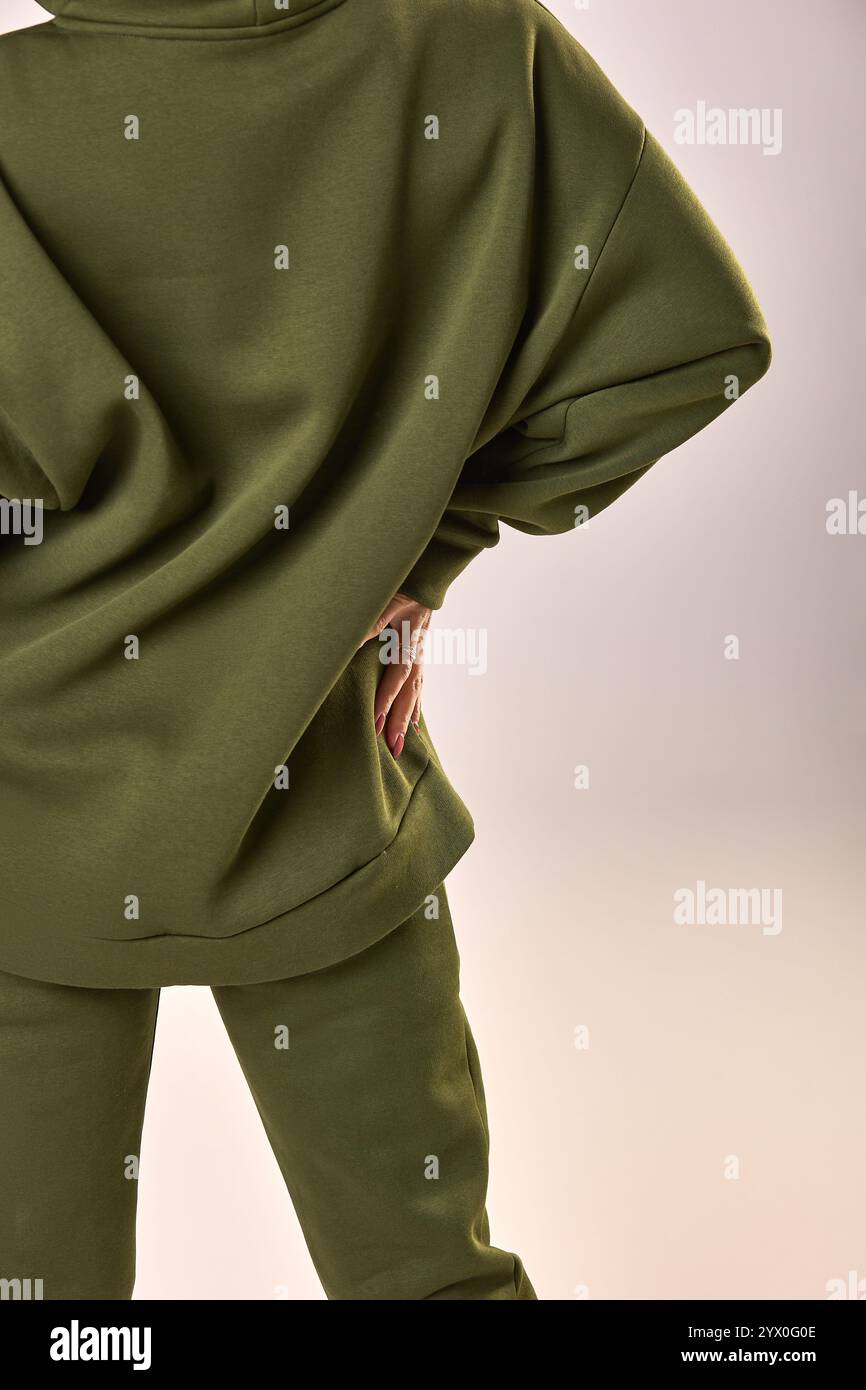 Posant en toute confiance femme dans la tenue vert olive à la mode, main sur la hanche dans un cadre moderne, concept de mode de vêtements élégant Banque D'Images