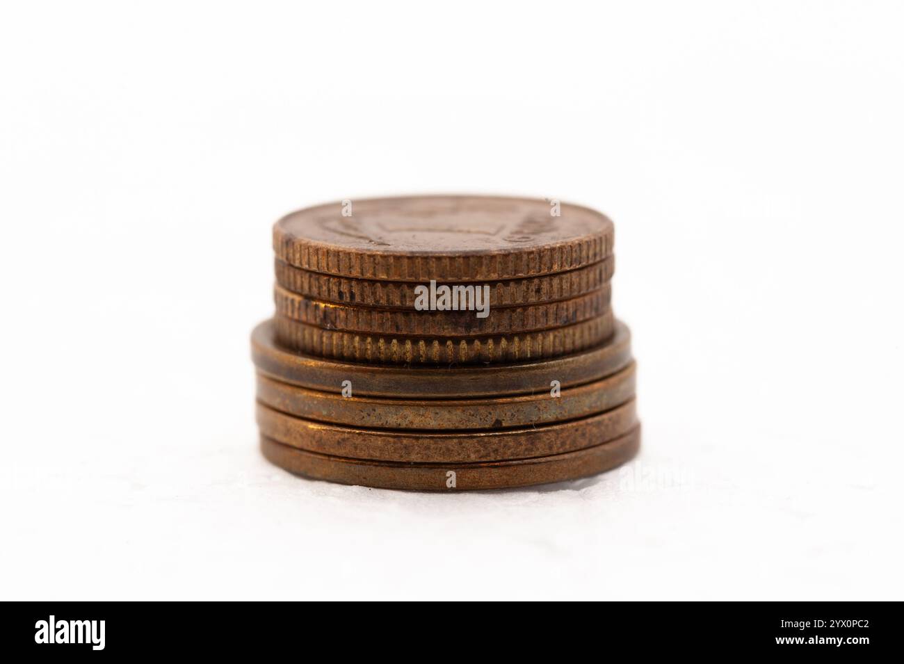 Une pile de pièces de monnaie sur un fond blanc. Les pièces sont de différentes tailles et couleurs. La pièce du haut est un quart, et la pièce du bas est un centime Banque D'Images