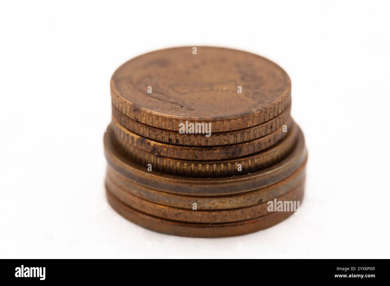 Une pile de pièces de monnaie sur un fond blanc. Les pièces sont de différentes tailles et couleurs. La pièce du haut est un quart, et la pièce du bas est un centime Banque D'Images