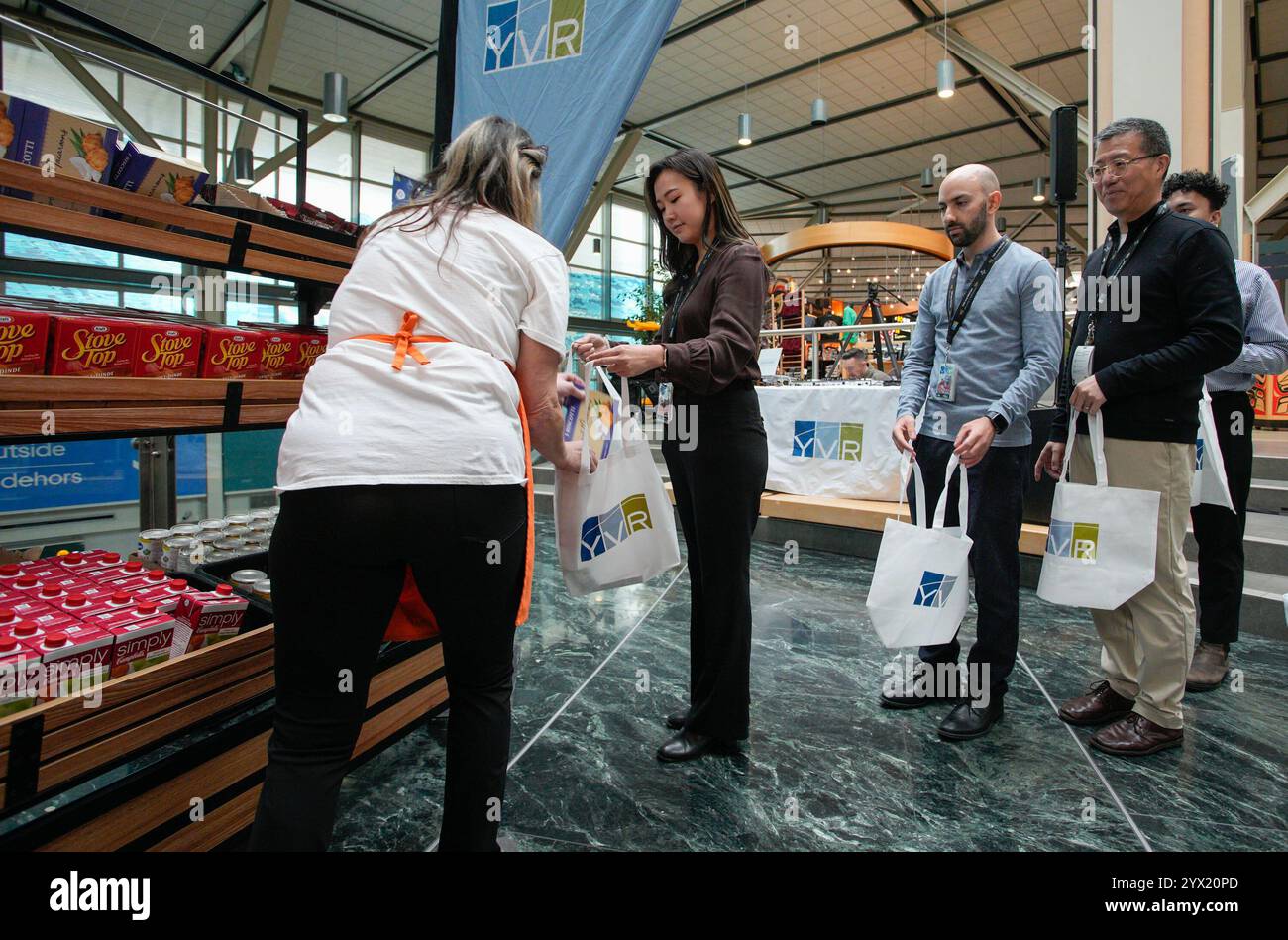 Richmond, Canada. 12 décembre 2024. Les gens font la queue pour acheter de la nourriture dans un « magasin éphémère » pour faire don lors de l'événement annuel Holiday Hamper Drive à l'aéroport international de Vancouver à Richmond, Colombie-Britannique, Canada, 12 décembre 2024. Plus d'un millier de sacs remplis de nourriture ont été donnés par le personnel de l'aéroport et les voyageurs pour aider les familles dans le besoin pendant la période des fêtes. Crédit : Liang Sen / Xinhua / Alamy Live News Banque D'Images