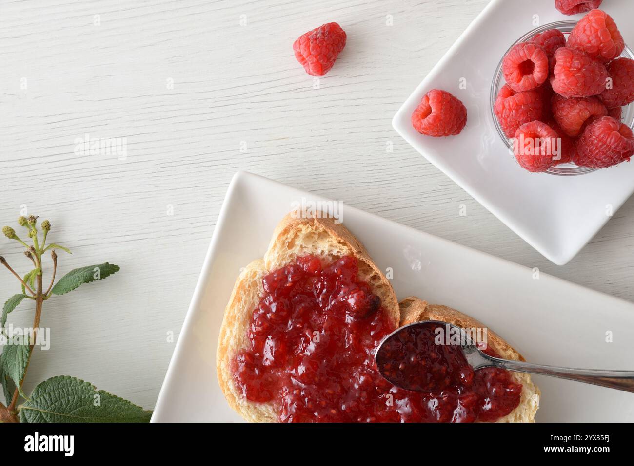 Griller avec de la confiture de framboises sur une assiette blanche fraîchement préparée pour le petit déjeuner et un bol plein de baies sur un banc en bois blanc. Vue de dessus. Banque D'Images
