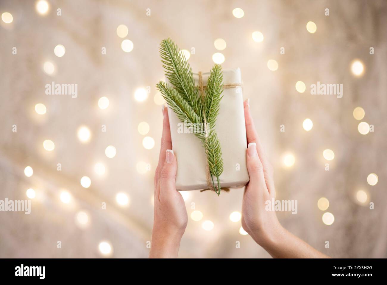 Femme tenant une boîte cadeau présente avec des lumières scintillantes derrière Banque D'Images