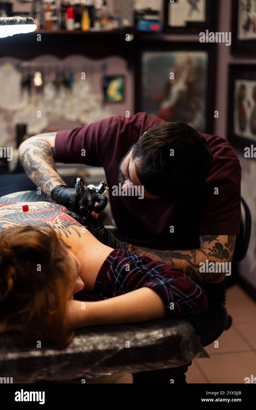 Un tatoueur fait un tatouage pour un client dans le studio Banque D'Images