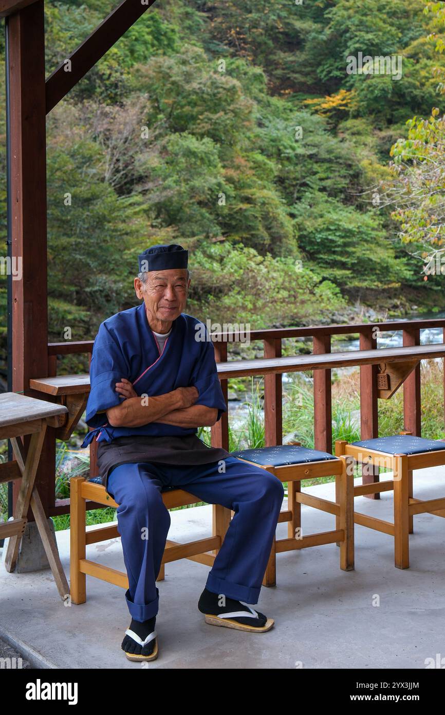 Un Japonais est assis à l'extérieur de son café au bord de la rivière. Banque D'Images