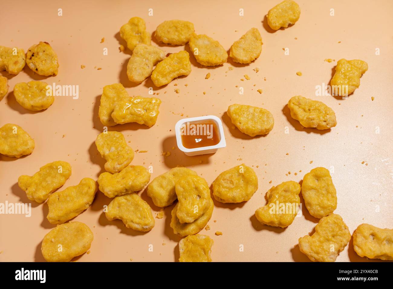 Un plateau de nuggets de poulet avec un petit récipient de sauce sur le dessus. Les pépites sont dispersées sur toute la table, et certaines d'entre elles sont mangées Banque D'Images