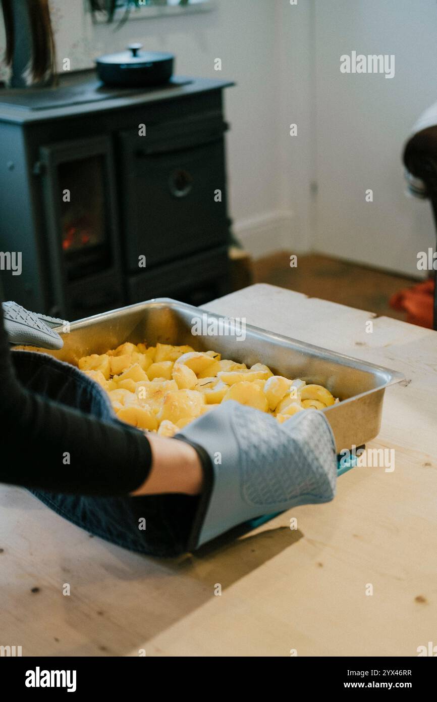 Une personne fait cuire des pommes de terre dans une casserole sur une table en bois. Les pommes de terre sont coupées en petits morceaux et sont cuites dans une poêle Banque D'Images