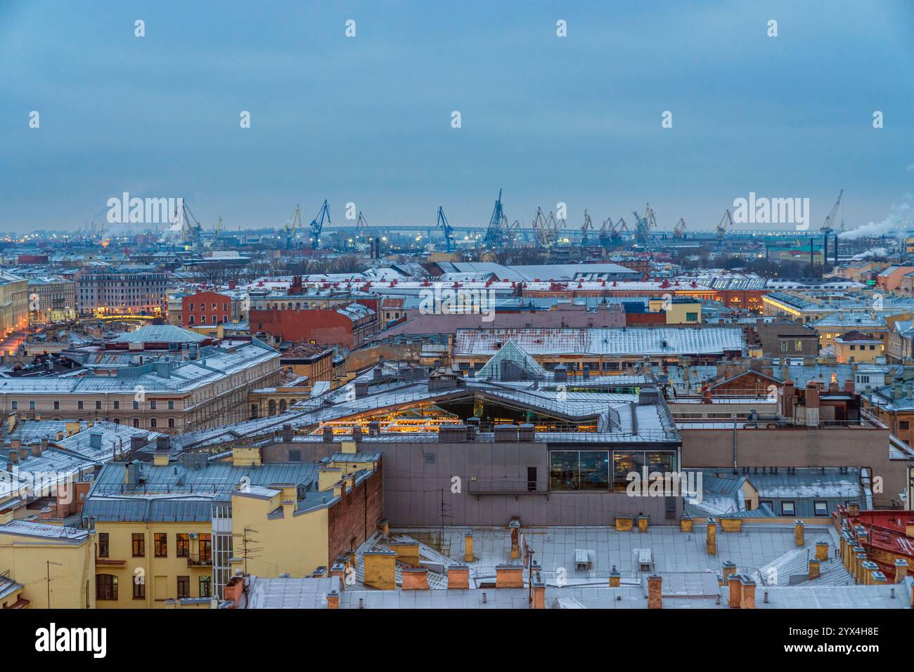 Un paysage urbain industriel avec des grues portuaires se levant derrière les bâtiments à Saint-Pétersbourg, en Russie, dans la soirée Banque D'Images