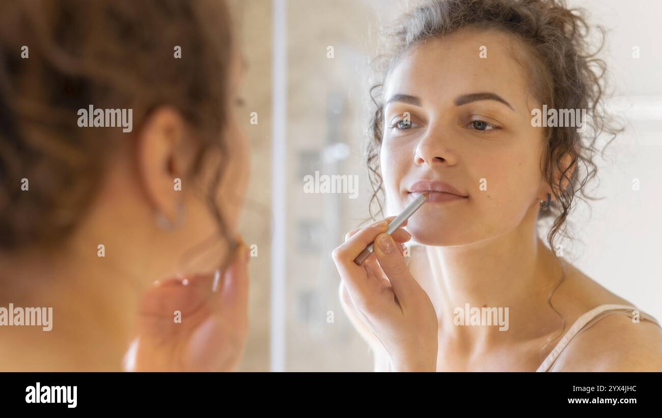 Femme regardant miroir appliquant du rouge à lèvres Banque D'Images