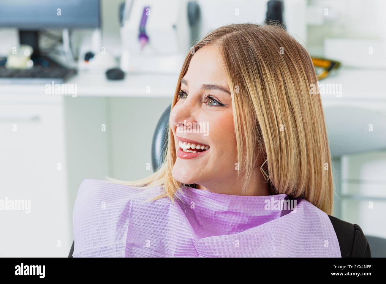 Jeune femme souriante tout en étant assise confortablement dans un fauteuil de dentiste, profitant d'un bilan dentaire dans une clinique moderne axée sur la santé bucco-dentaire Banque D'Images