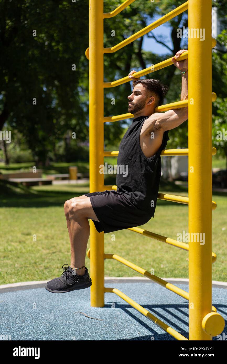 Fit jeune homme effectuant des exercices abdominaux sur des barres extérieures Banque D'Images