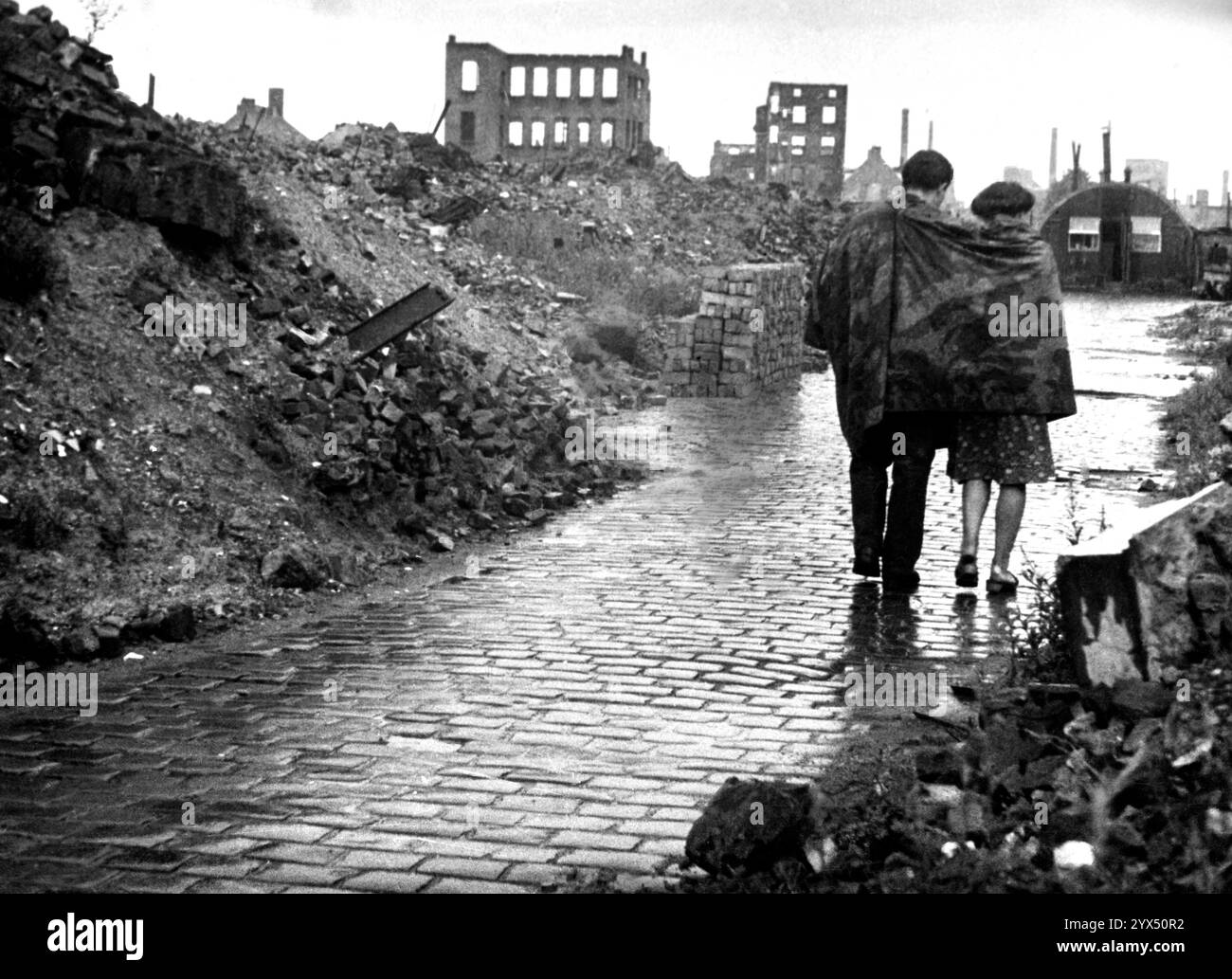 1947 Hambourg Barmbek, Heitmannstraße, couple entre ruines, avec une tente en toile Wehrmacht autour de leurs épaules contre la pluie. [traduction automatique] Banque D'Images