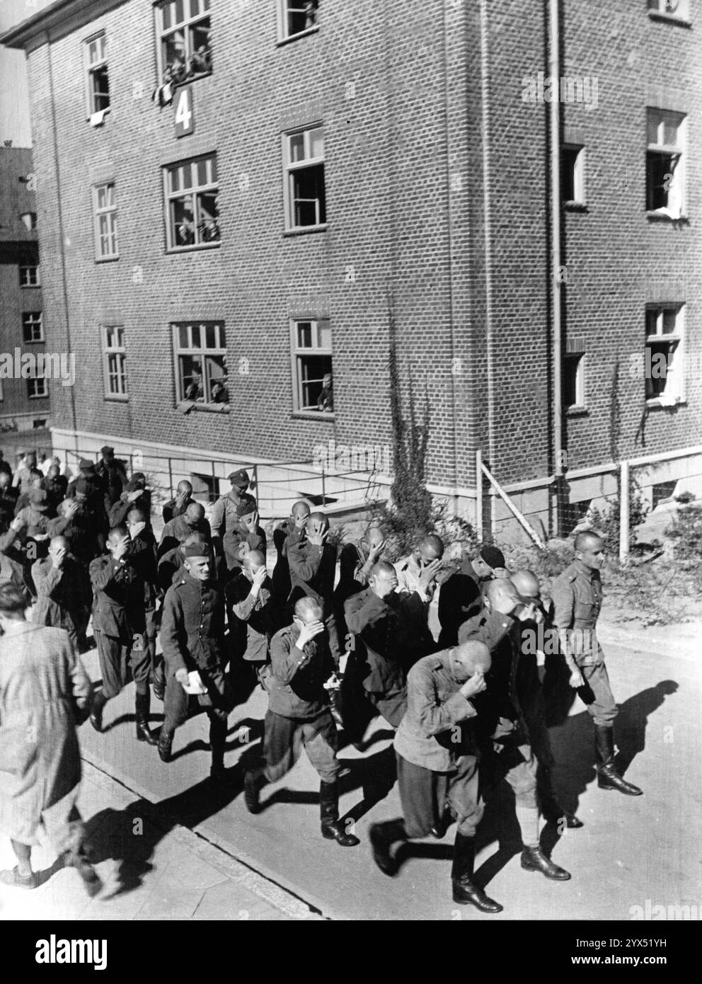 Prisonniers polonais dans le camp de prisonniers d'Itzehoe, Schleswig-Holstein, en train d'être rassemblés par des officiers SS. Tous les prisonniers se couvrent le visage avec leurs mains devant le photographe. [traduction automatique] Banque D'Images