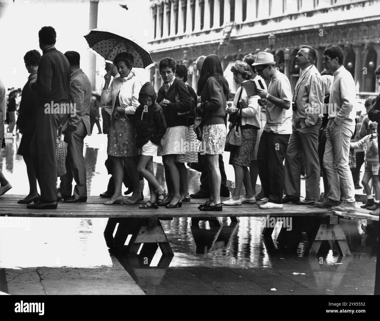 Italie 1969 Venise : place Marc sous la pluie, les touristes marchent sur des planches à cause des crues. [traduction automatique] Banque D'Images