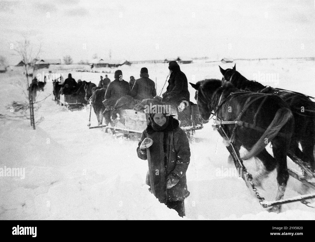 Russie 1942, hiver : soldats allemands sur des charrettes tirées par des chevaux dans la neige, femme russe avec une pelle. [traduction automatique] Banque D'Images