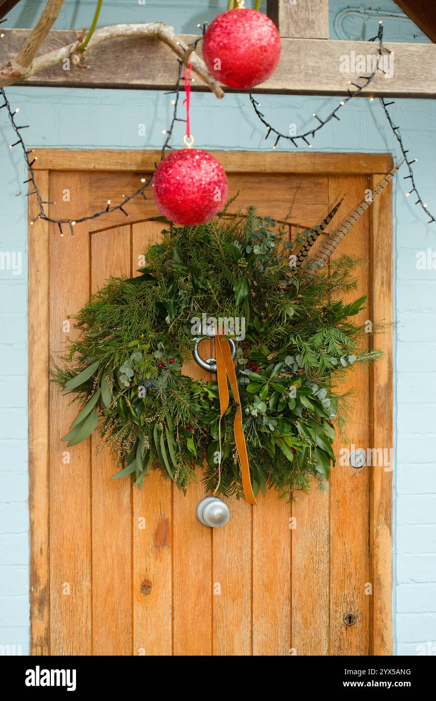 Couronne de Noël traditionnelle faite maison sur une porte d'entrée. Décorations de Noël dans une maison en Angleterre, Royaume-Uni. Banque D'Images
