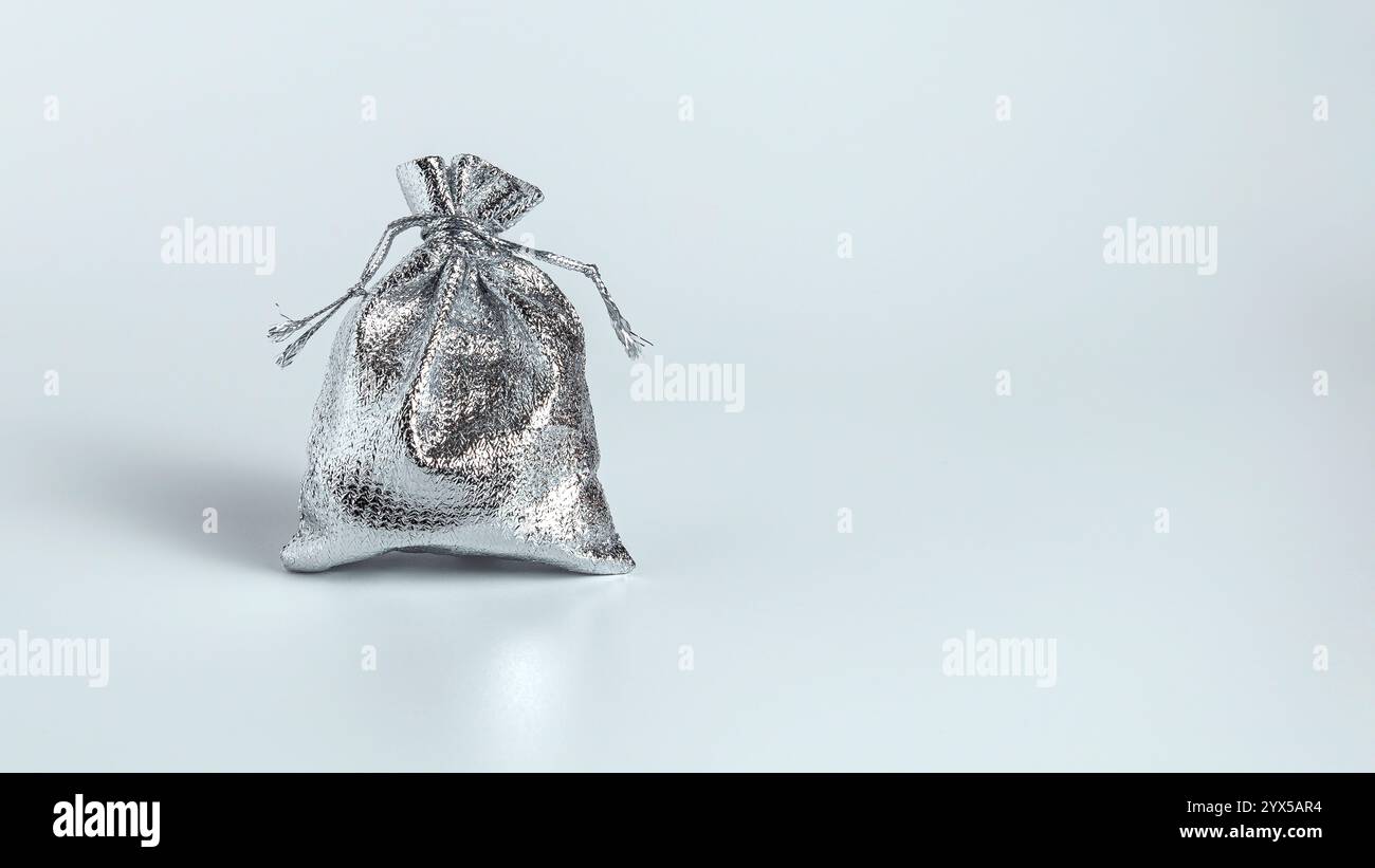Cadeau de Noël dans un sac argenté sur fond blanc. Copier l'espace. Banque D'Images