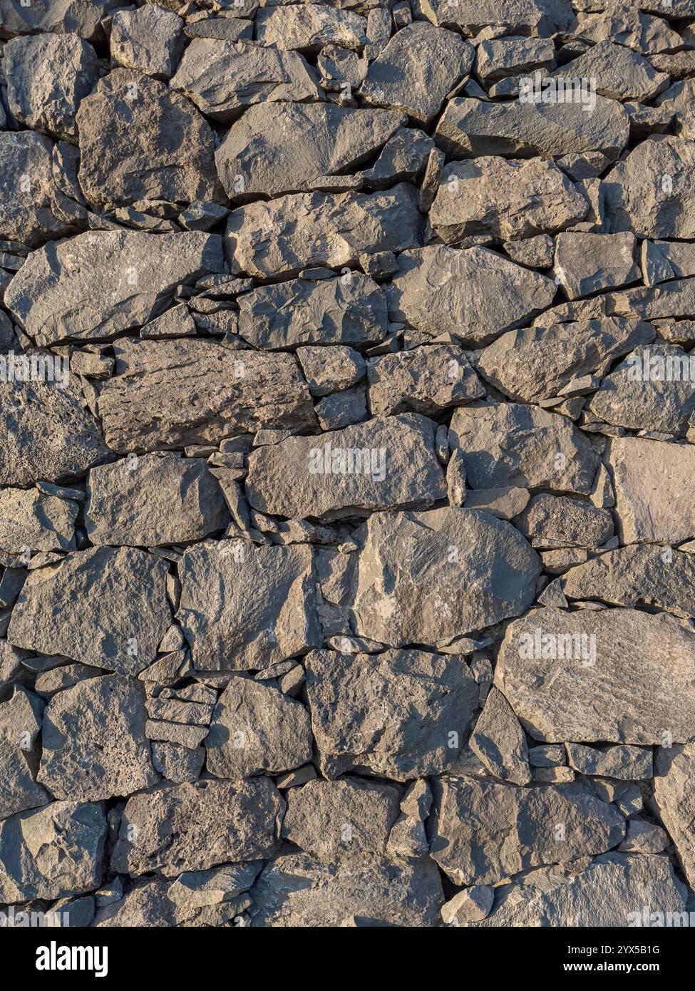 Fond d'un mur de pierre empilé de roche volcanique. Prise de vue verticale. Banque D'Images