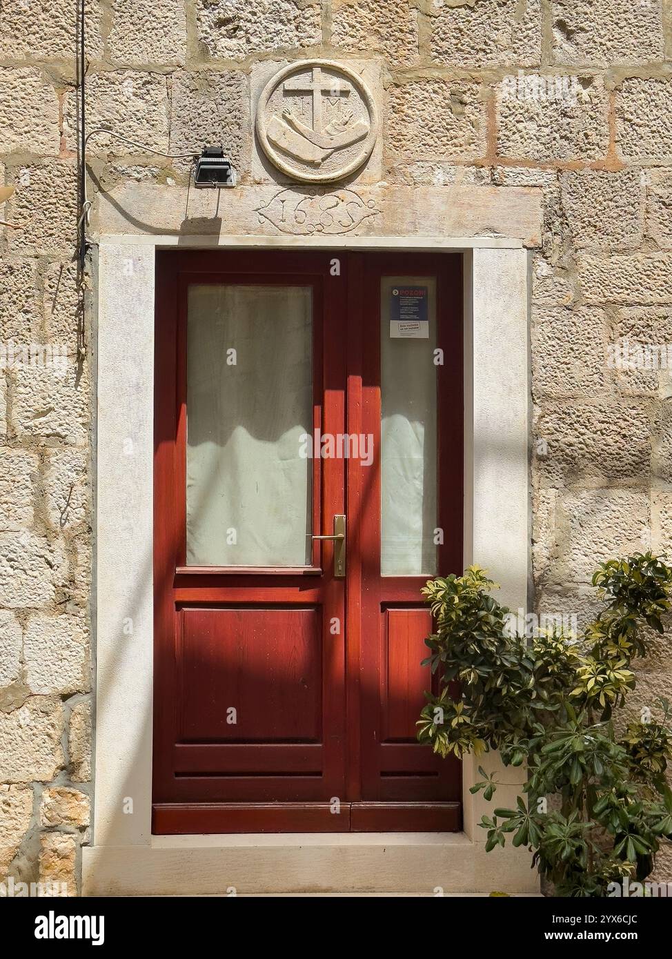 Korcula, Croatie - 30 juin 2024 : ruelle Koparova, place devant l'église All Saints. Signe de croix spécial au-dessus de la porte : caractères I et M signifiant Jesu Banque D'Images