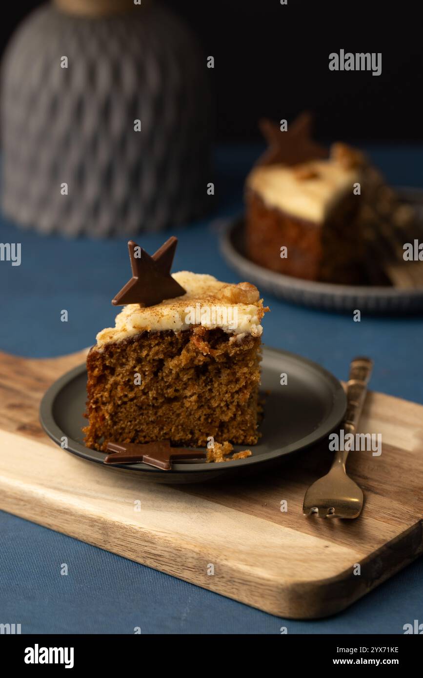 deux tranches de gâteau aux carottes avec glaçage crémeux et un topper de chocolat en forme d'étoile, servies sur une petite assiette et une planche avec une fourchette à gâteau Banque D'Images