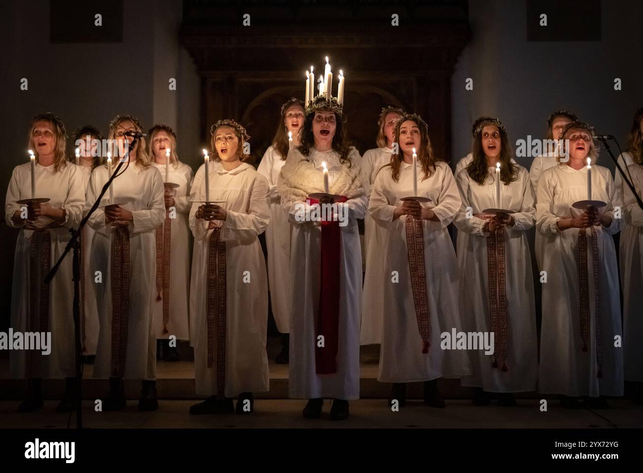 Londres, Royaume-Uni. 13 décembre 2024. Célébrations de Sankta Lucia par Norrsång East London Swedish Choir à l’église St Mary de Walthamstow. Alma Fridell Crawshaw porte une couronne de bougies symbolisant Sainte Lucy alors qu’elle dirige la célébration de Sankta Lucia, basée sur la bravoure et le martyre d’une jeune sicilienne Sainte Lucy (Lucie de Syracuse 283-304). Crédit : Guy Corbishley/Alamy Live News Banque D'Images