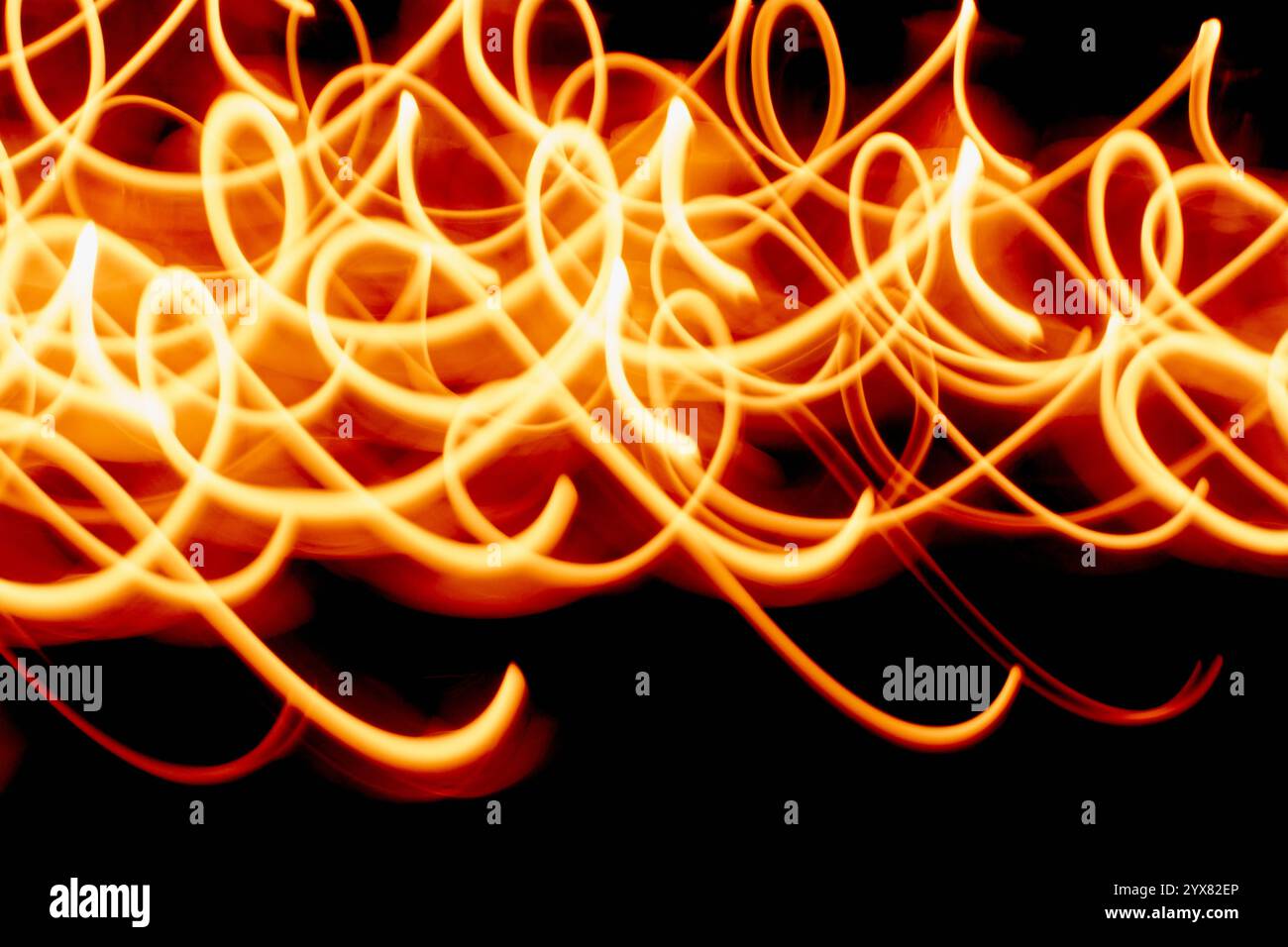 Cette image présente des traînées de lumière dynamiques créant des motifs abstraits sur un fond orange éclatant, parfait pour les projets créatifs nécessitant de l'énergie Banque D'Images