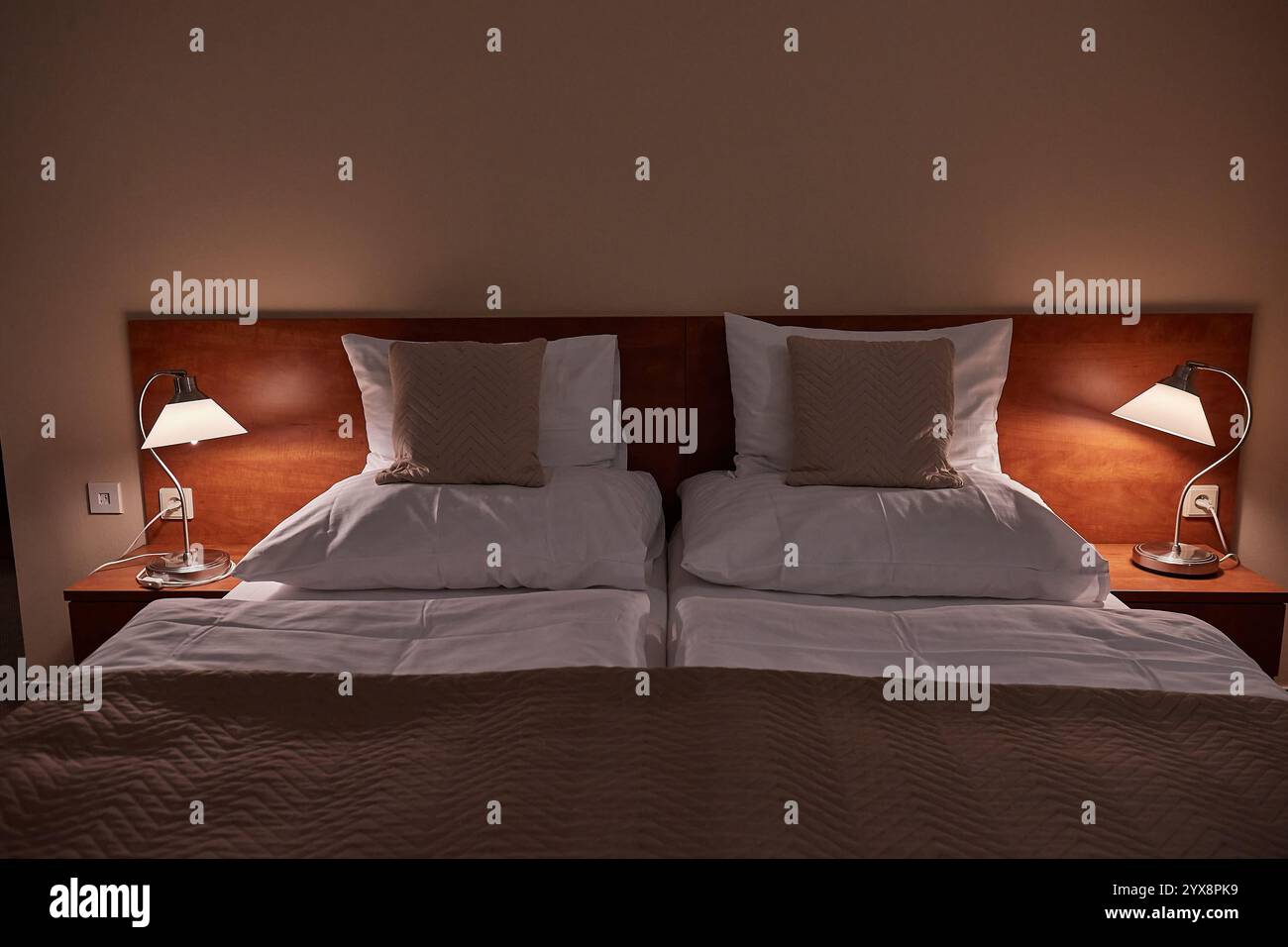 Lit d'hôtel avec draps blancs, éclairage confortable Banque D'Images