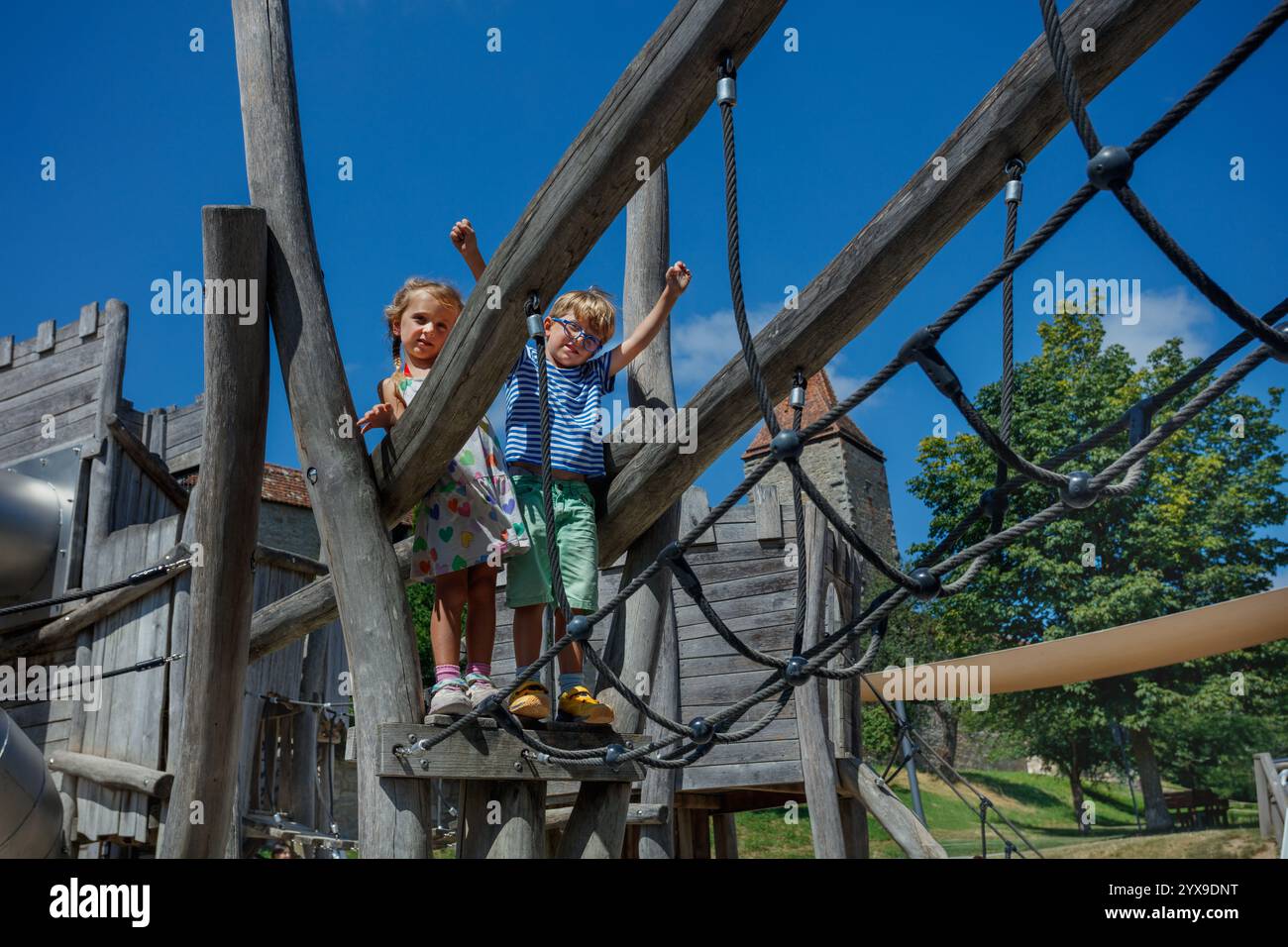 Enfants garçon et fille à la structure de jeu en bois le jour ensoleillé à l'extérieur Banque D'Images