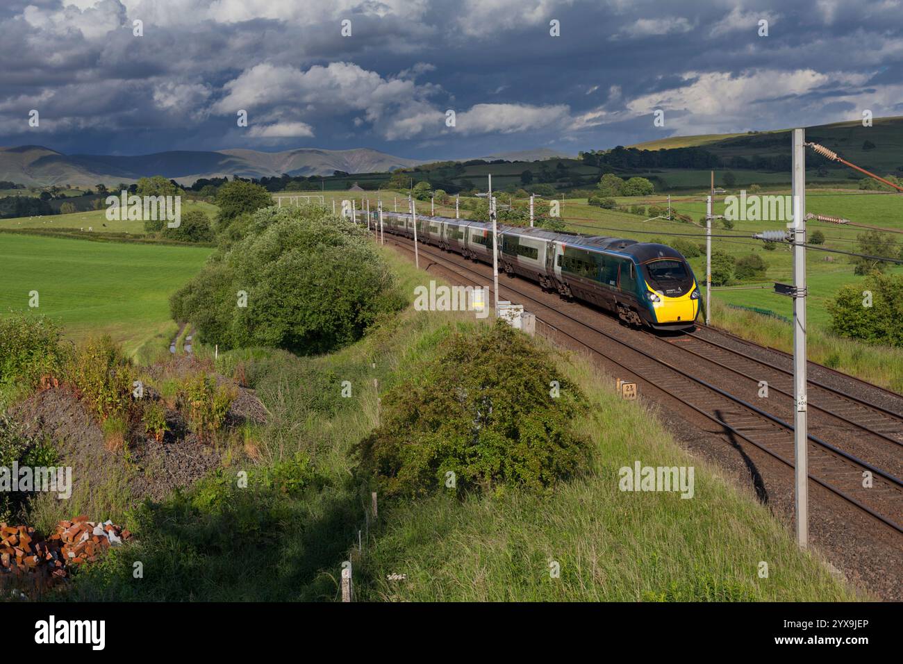 Avanti West Coast Alstom Pendolino train 390112 sur la ligne principale de la côte ouest en Cumbria avec un ciel noir et une campagne pittoresque Banque D'Images