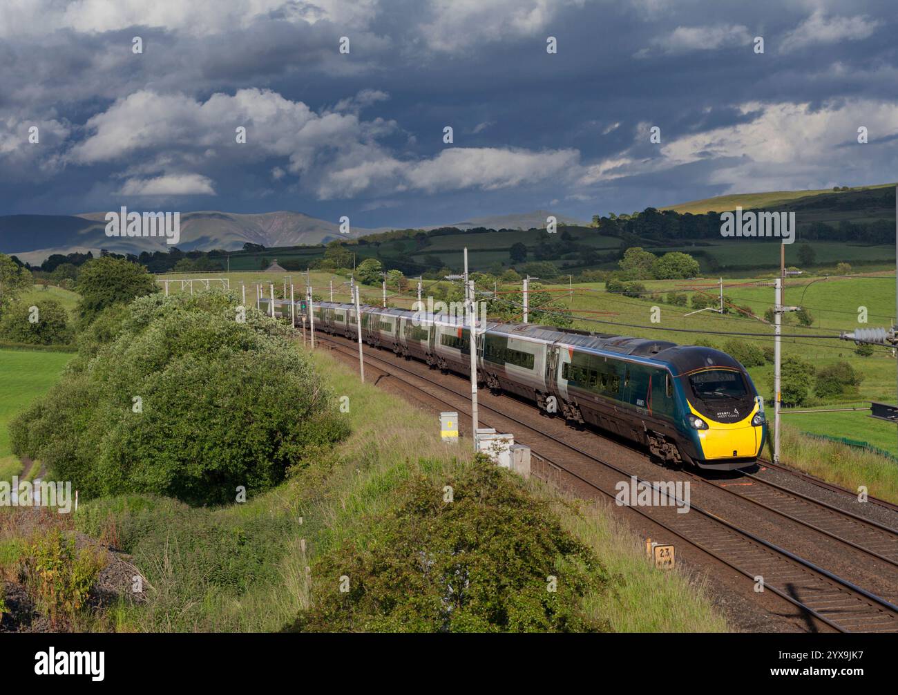 Avanti West Coast Alstom Pendolino train 390112 sur la ligne principale de la côte ouest en Cumbria avec un ciel noir et une campagne pittoresque Banque D'Images