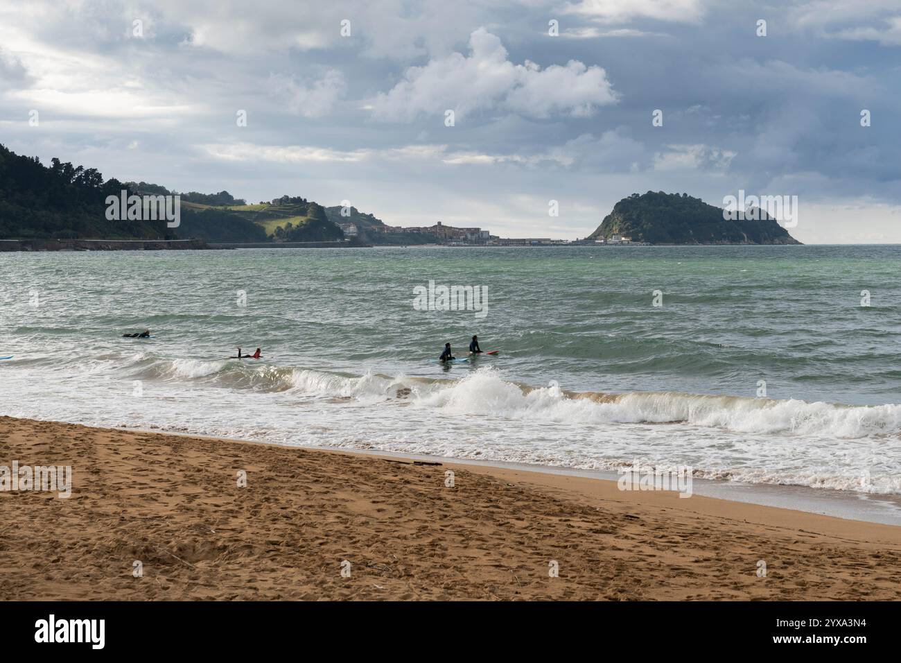 Les surfeurs s'entraînent à attraper les vagues à Playa de Zarautz à Zarautz, pays Basque, Espagne. Le village balnéaire populaire se trouve le long de la route Camino del Norte Banque D'Images