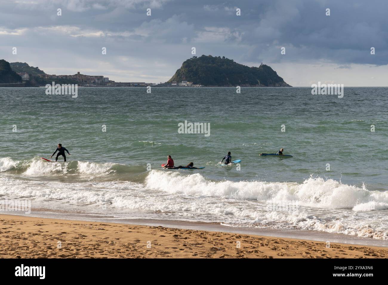 Les surfeurs s'entraînent à attraper les vagues à Playa de Zarautz à Zarautz, pays Basque, Espagne. Le village balnéaire populaire se trouve le long de la route Camino del Norte Banque D'Images