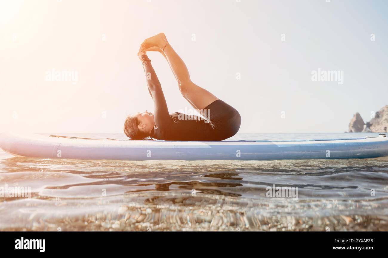 Yoga Paddleboard pose Ocean - homme faisant une pose de yoga sur paddleboard dans l'eau de l'océan. Banque D'Images