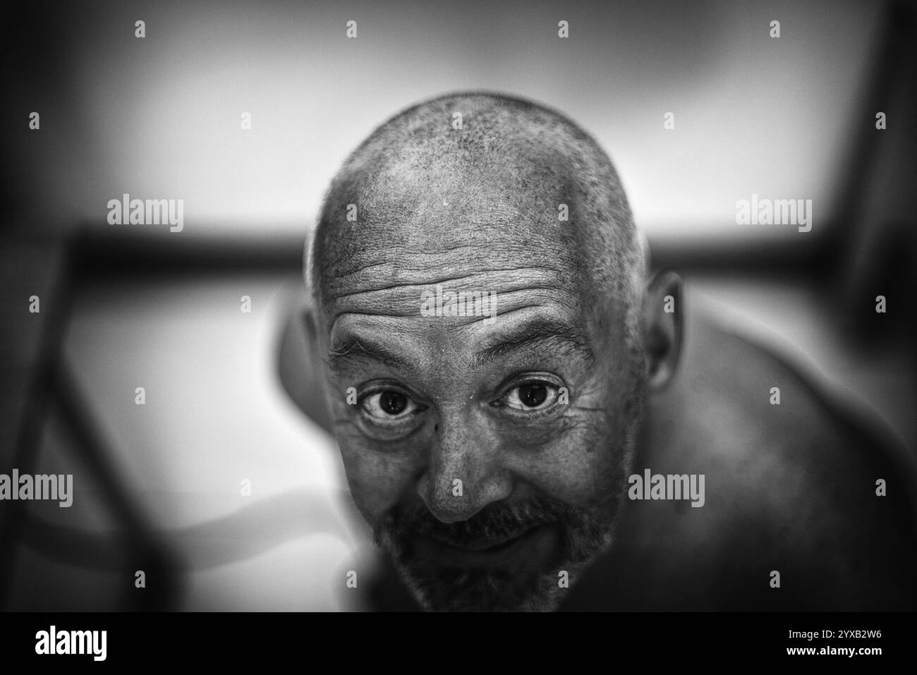 Homme avec une tête rasée et un regard dérangeant, indiquant une détresse mentale Banque D'Images