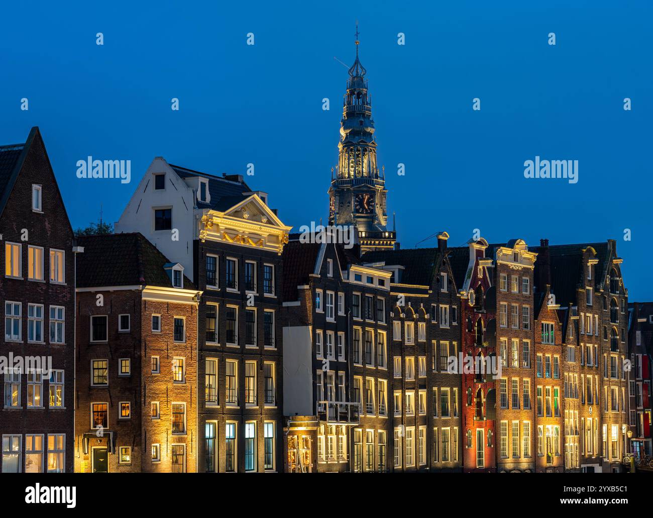 Amsterdam damrak et la tour de l'oude kerk dans la soirée, maisons hollandaises pittoresques au bord du canal Banque D'Images