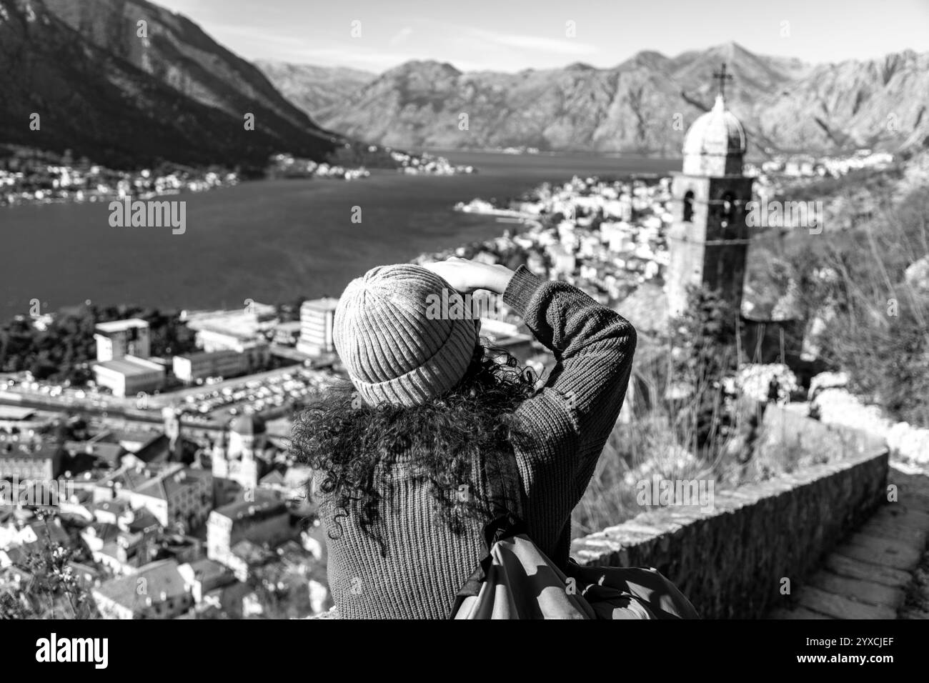 Kotor, Monténégro - 14 février 2024 : visiteur aux cheveux bouclés prenant des photos panoramiques de la baie de Kotor depuis le château de Kotor. Banque D'Images